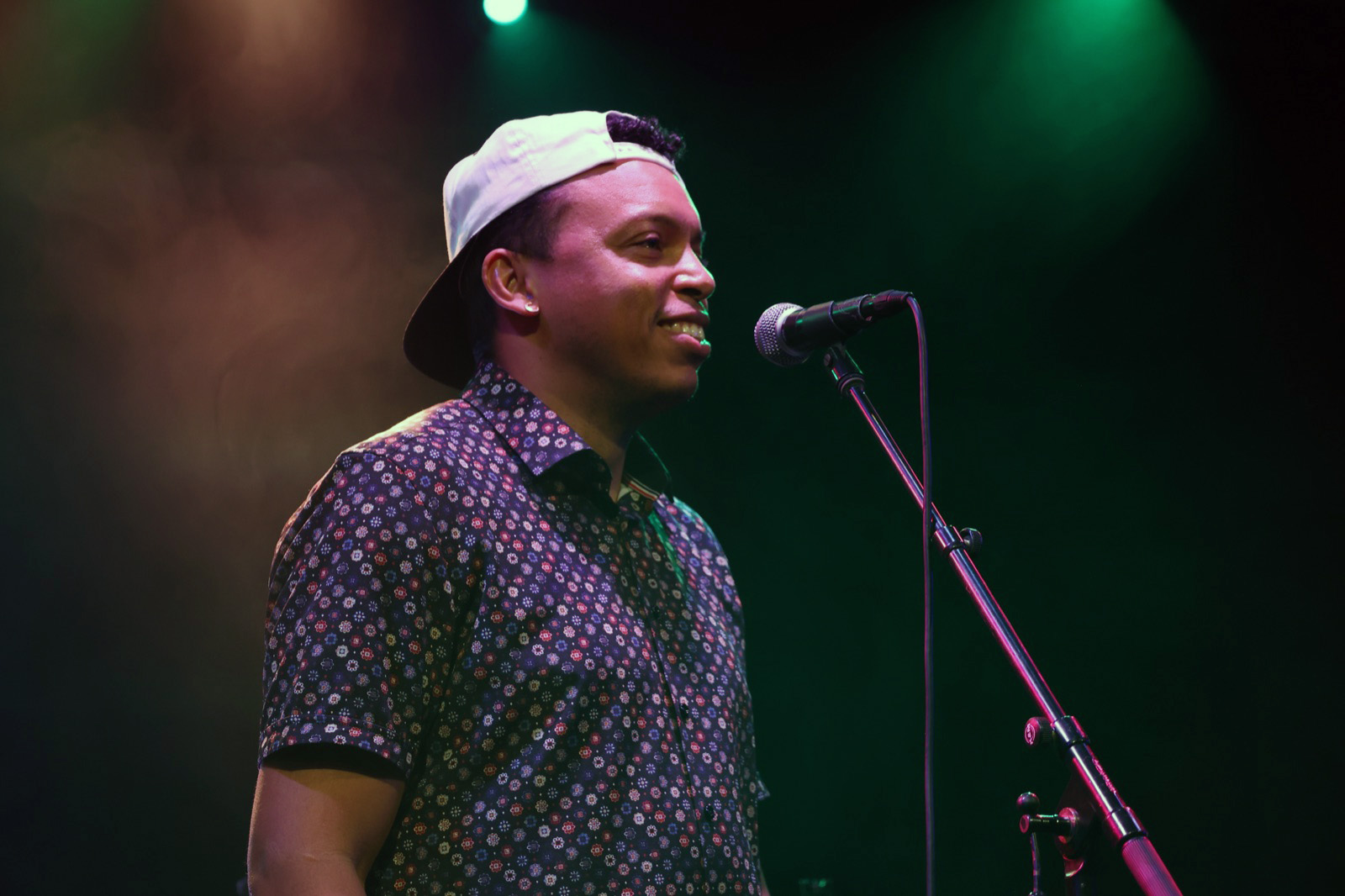 Chris Mayers smiling at the microphone under green stage lighting