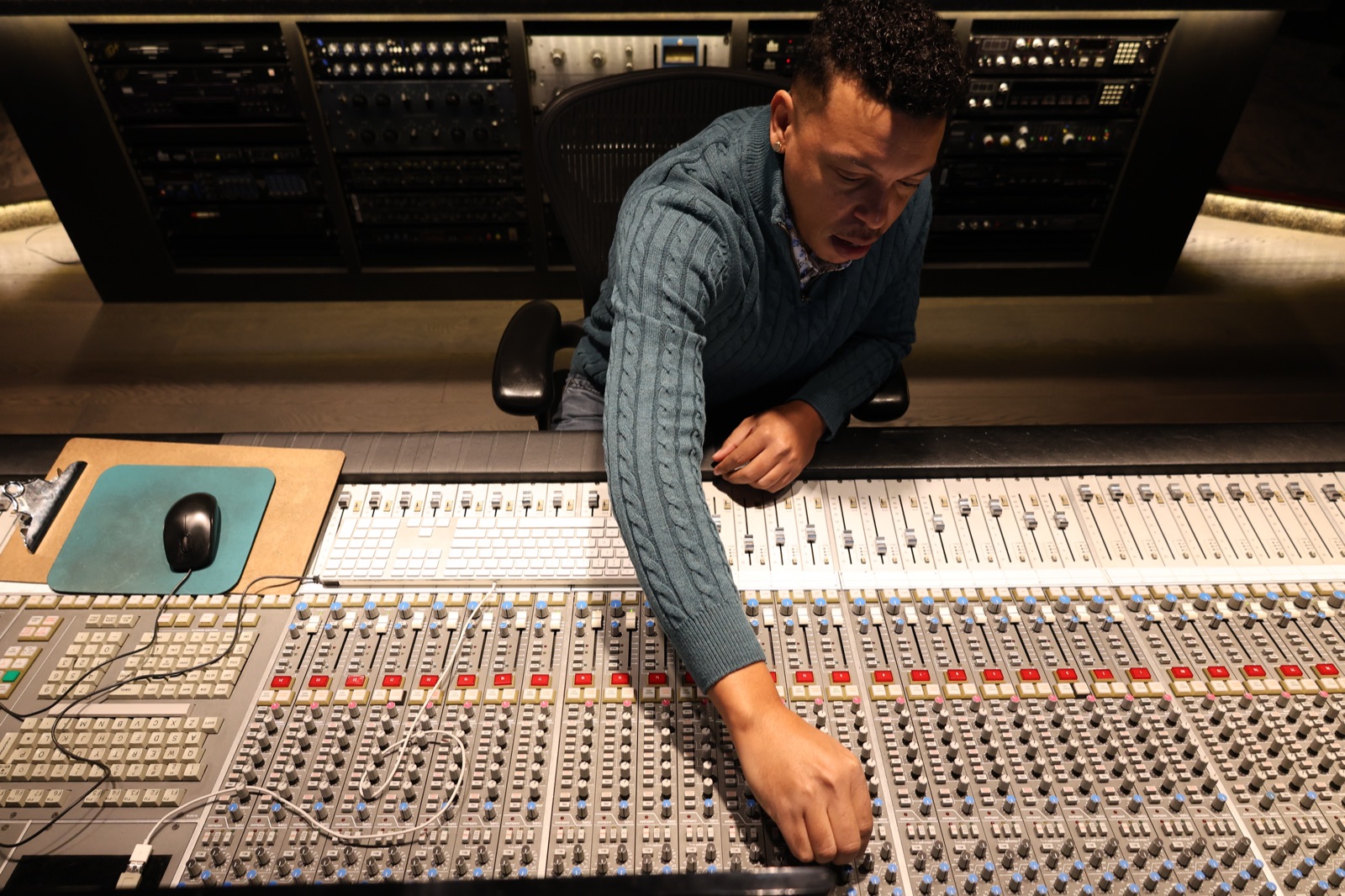 Chris Mayers adjusting faders on a large mixing console mid-session