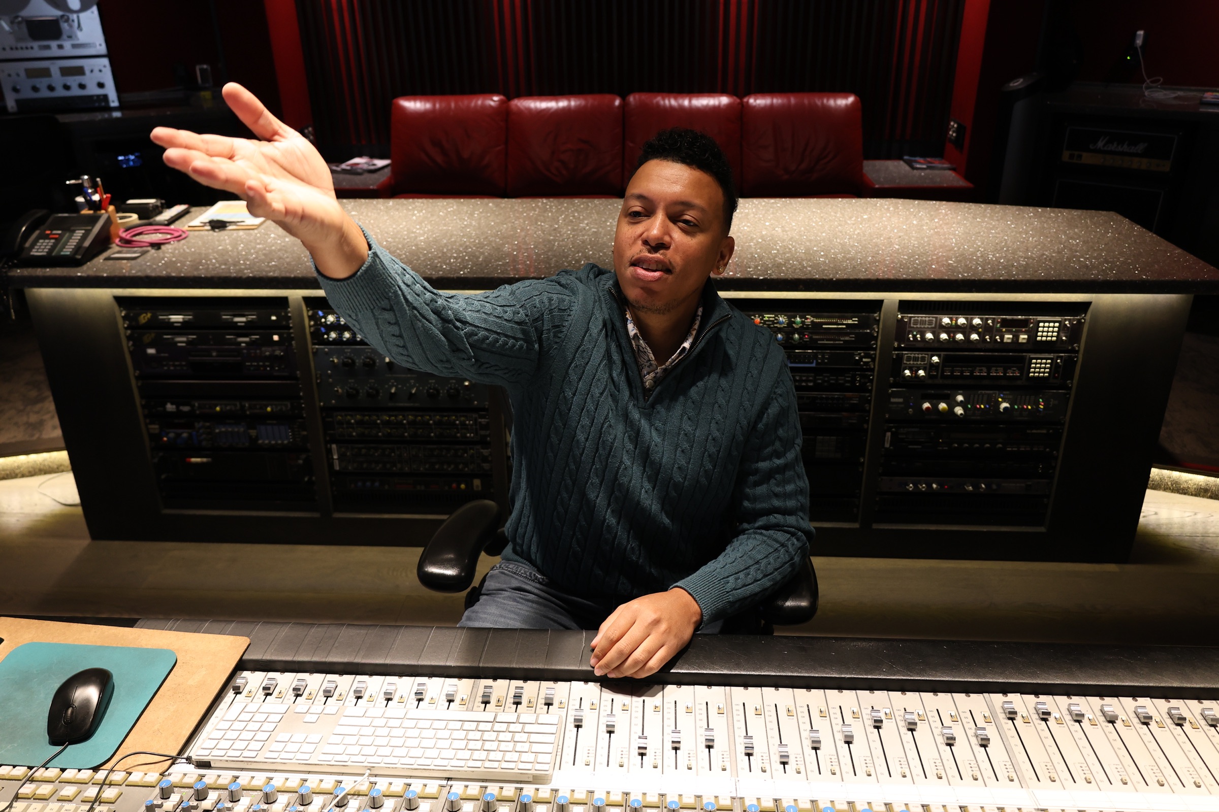 Chris Mayers at a large mixing console in the studio, outboard racks behind him